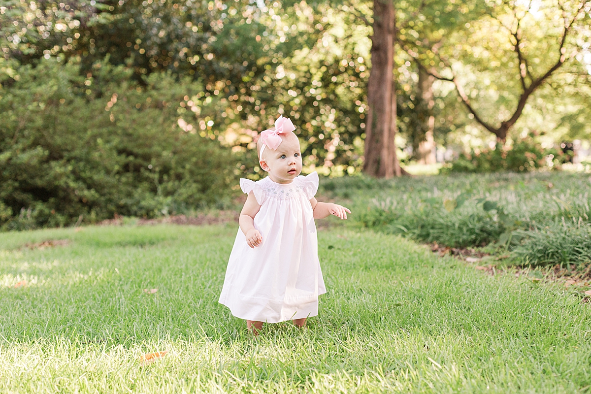 one year old girl standing in grass during first year milestone portraits