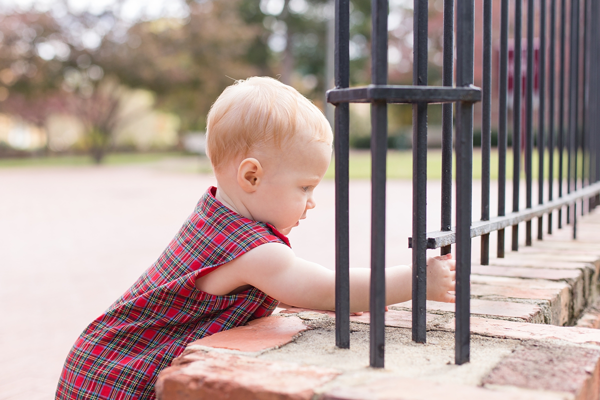 curious baby boy touches gate 