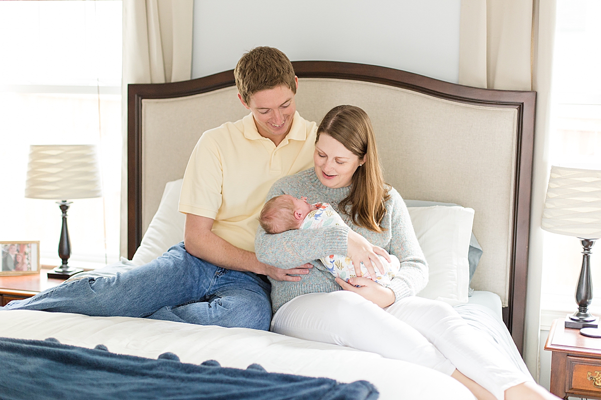 parents pose with baby boy on bed