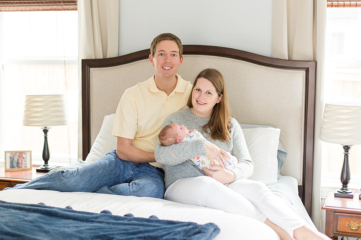 parents sit on bed during In-Home Newborn Lifestyle Session