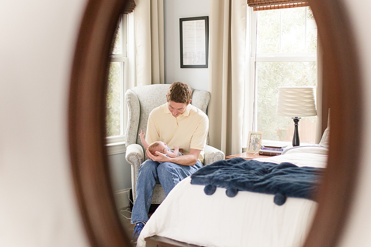dad looks down at son during newborn photos at home