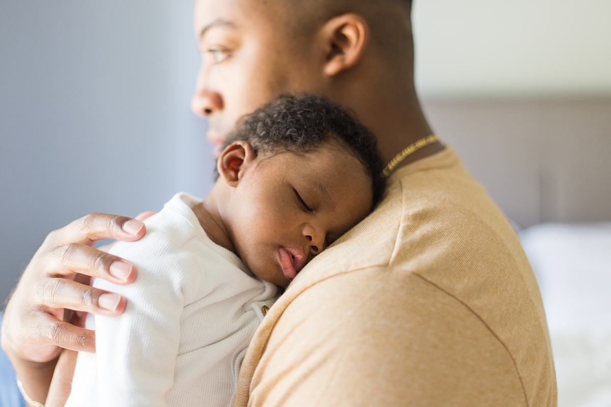 baby falls asleep on dad's shoulder during newborn photos