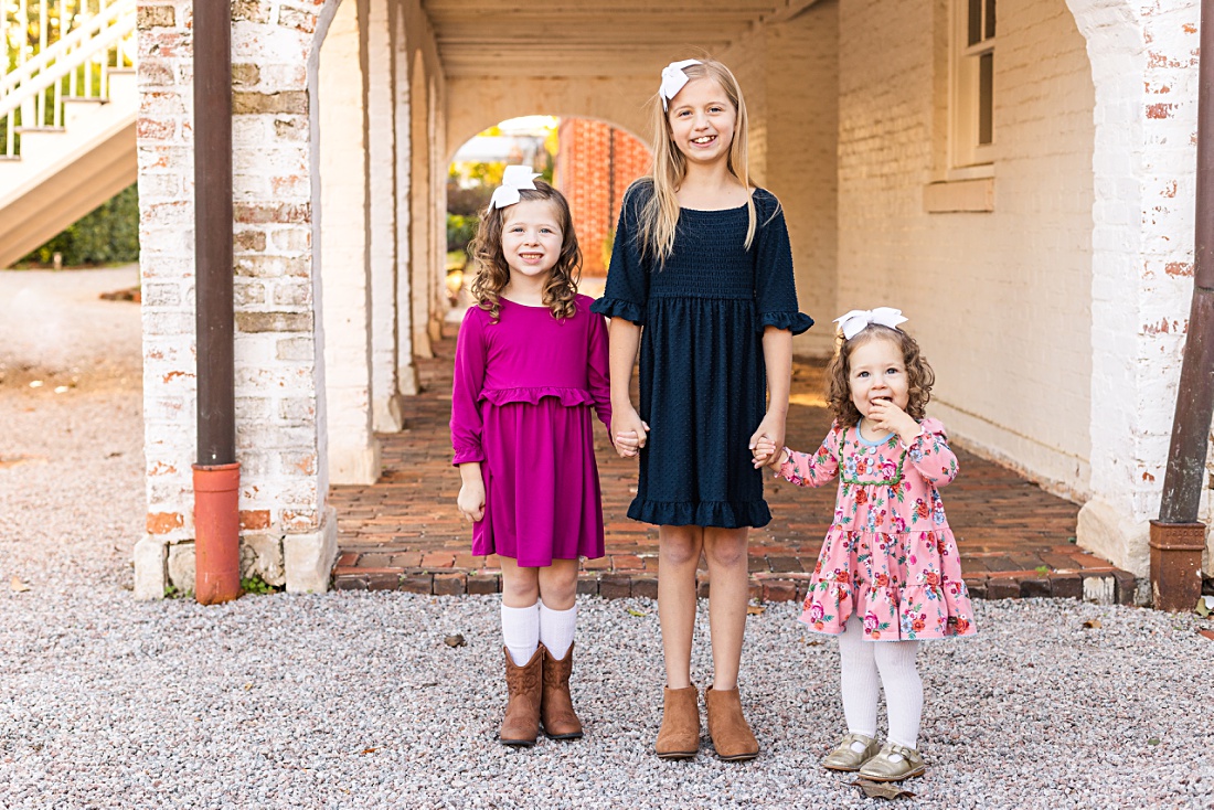 three sisters holding hands and smiling during fall mini session event with Nicole Watford Photography in Columbia, SC