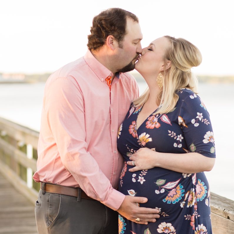 a kiss between expectant parents on a dock at Lake Murray, SC